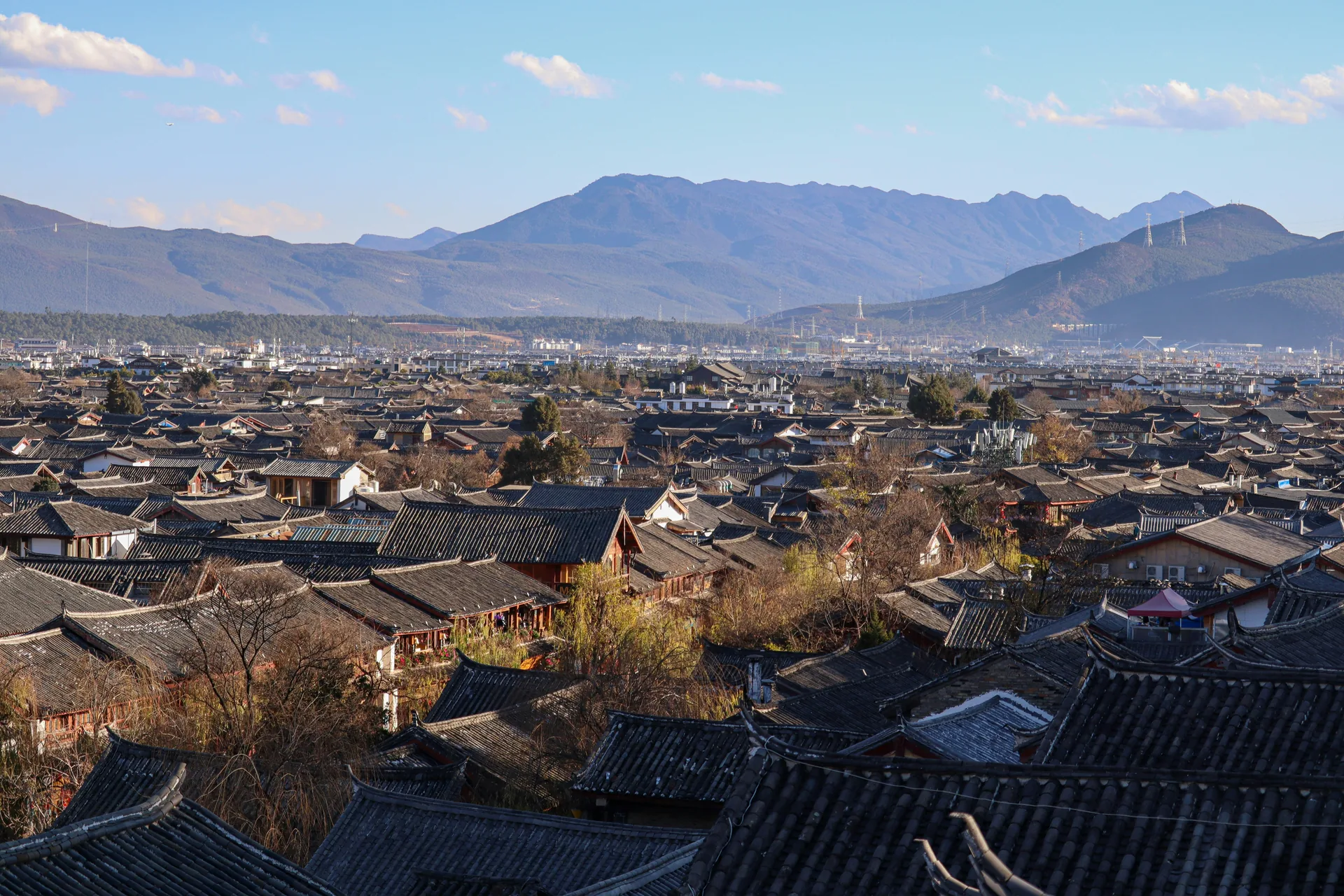 Lijiang old-town rooftops and mountains. Destination context; the selected programme confirms included visits.
